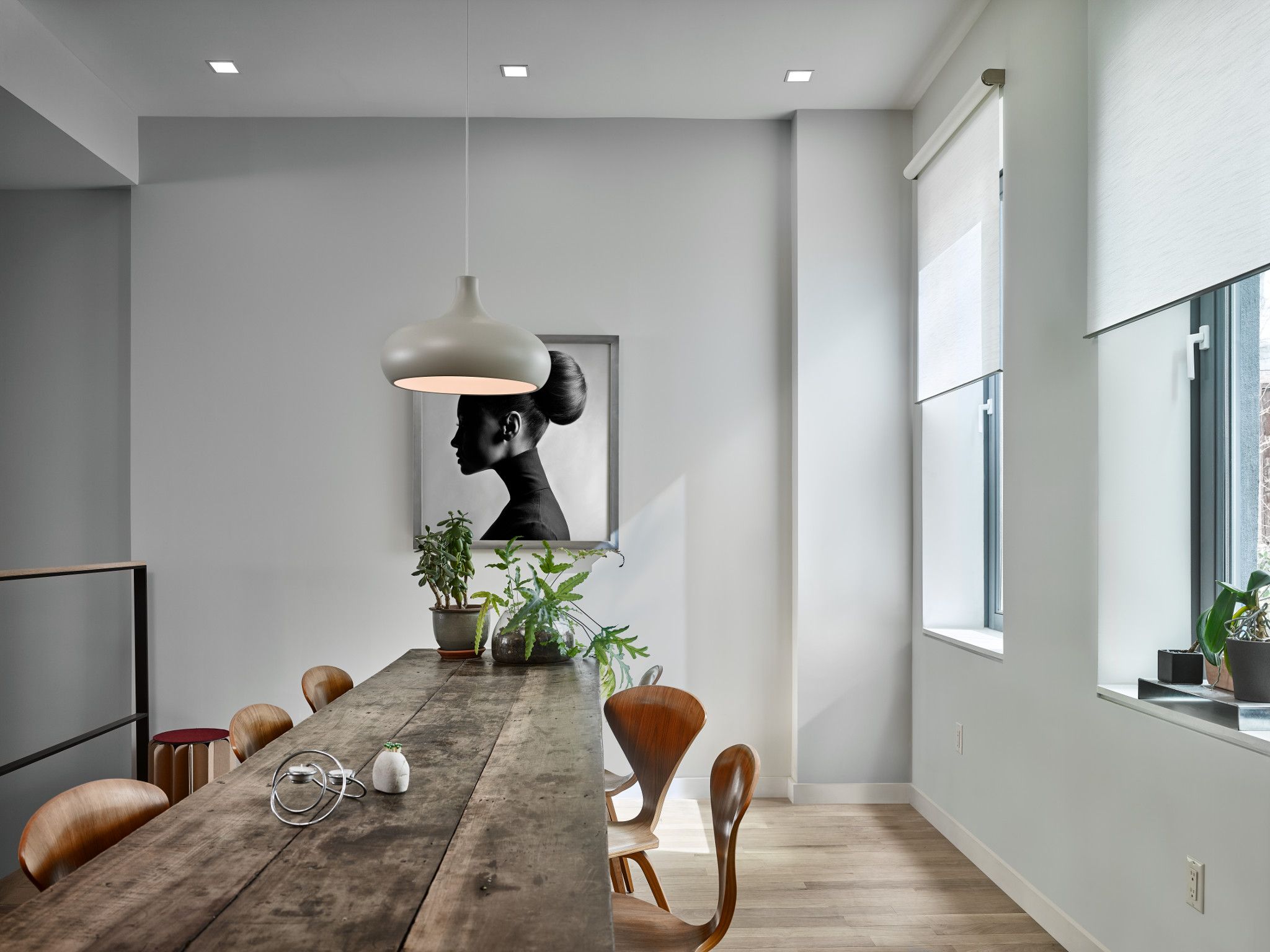 Contemporary dining room with motorized roller shades softly diffusing natural light through tall side windows